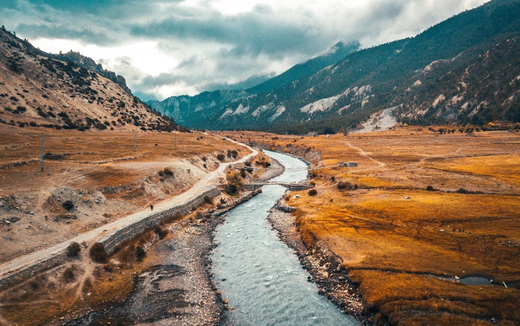 A winding mountain river cutting through golden Himalayan foothills in Nepal.