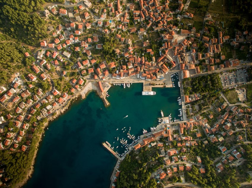 Aerial view of a coastal Croatian village clustered around a sheltered harbor.