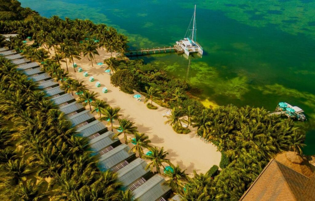 Bungalows Key Largo’s palm-fringed beach dotted with turquoise cabanas and a sailboat dock