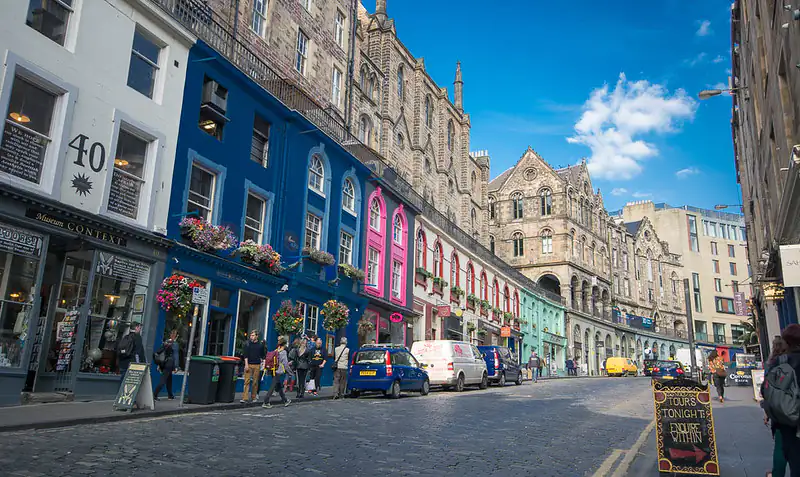Colorful Victorian-era shops line Edinburgh’s Victoria Street under clear summer skies, Scotland