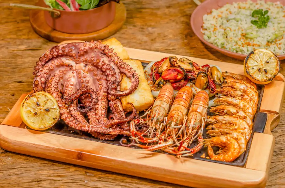 Grilled octopus, prawns, and mussels arranged on a wooden board at Sting Ray’s Seafood