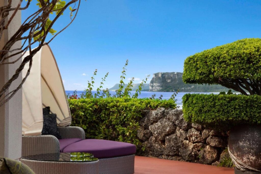 Hilton Guam’s ocean-view patio framed by sculpted hedges and distant limestone cliffs