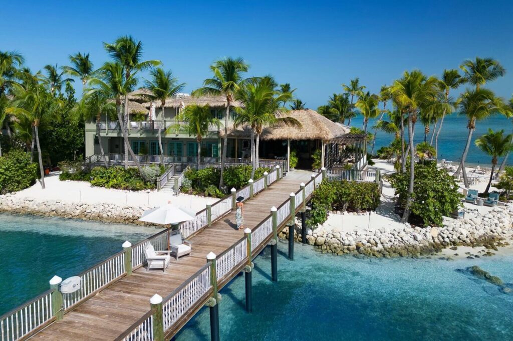 Little Palm Island’s over-water pier leading to a thatched-roof hideaway on turquoise flats