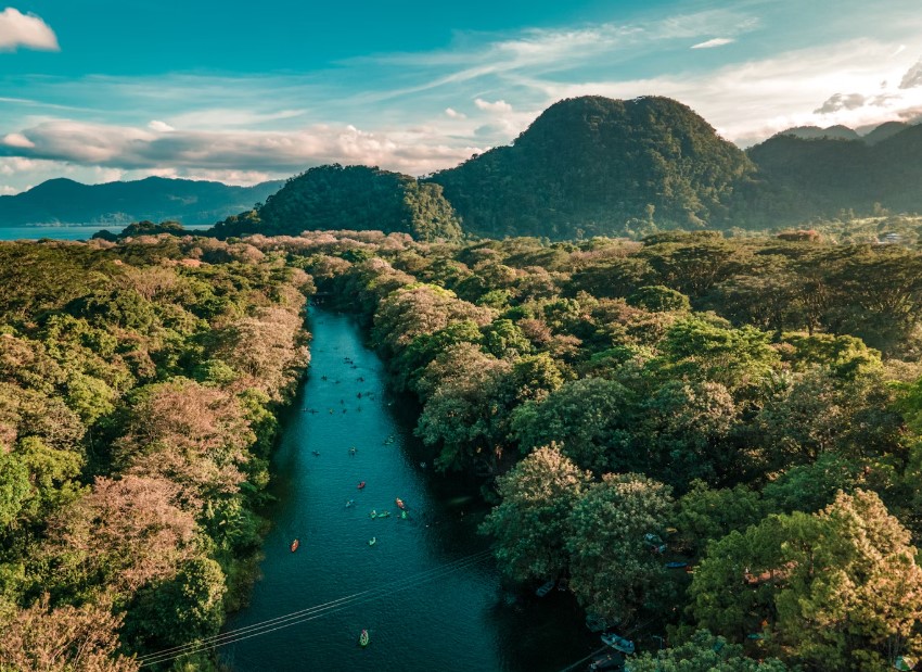 Paddlers drifting through lush jungle along Honduras’s Canal del Kayak at golden hour.