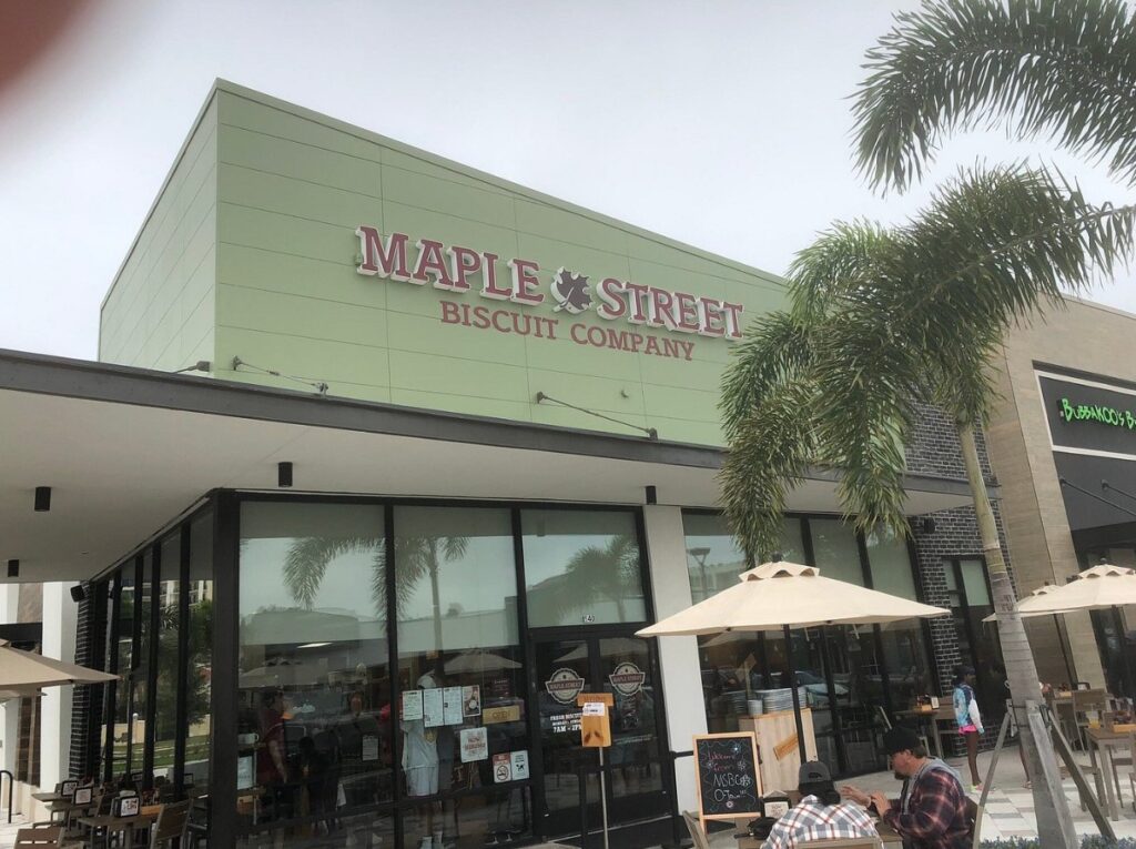 Pale-green façade of Maple Street Biscuit Company shaded by breezy palms