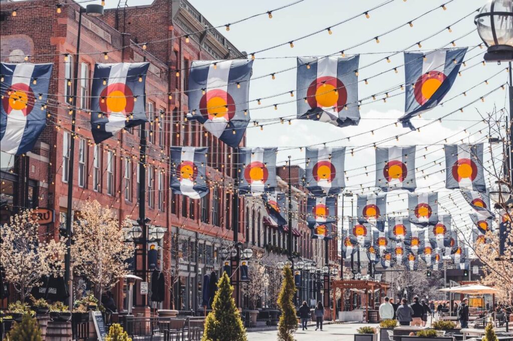 String-lit Colorado flags fluttering above historic brick storefronts in Larimer Square, Denver