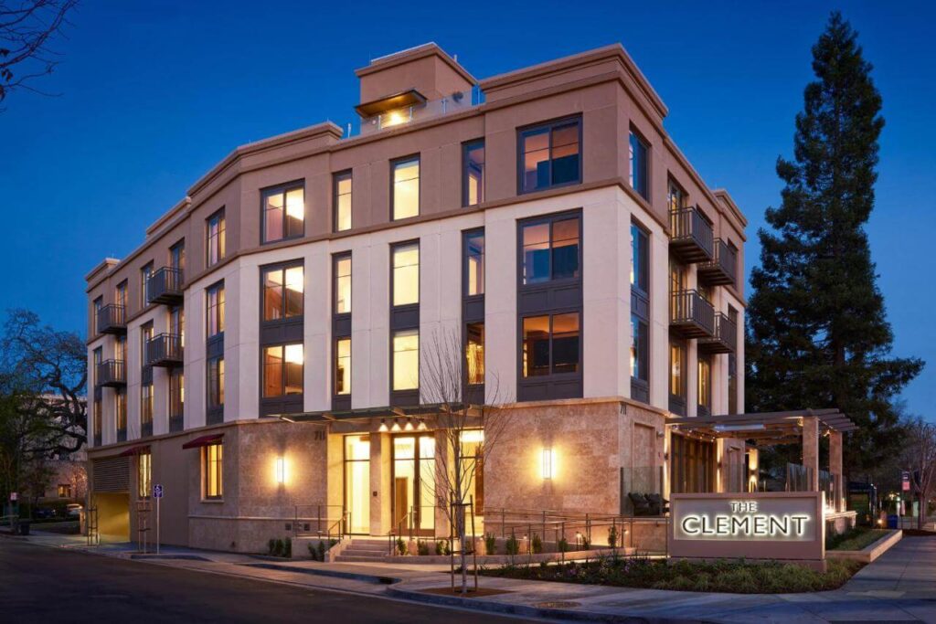 The Clement Hotel’s modern façade aglow at dusk on a leafy Palo Alto street