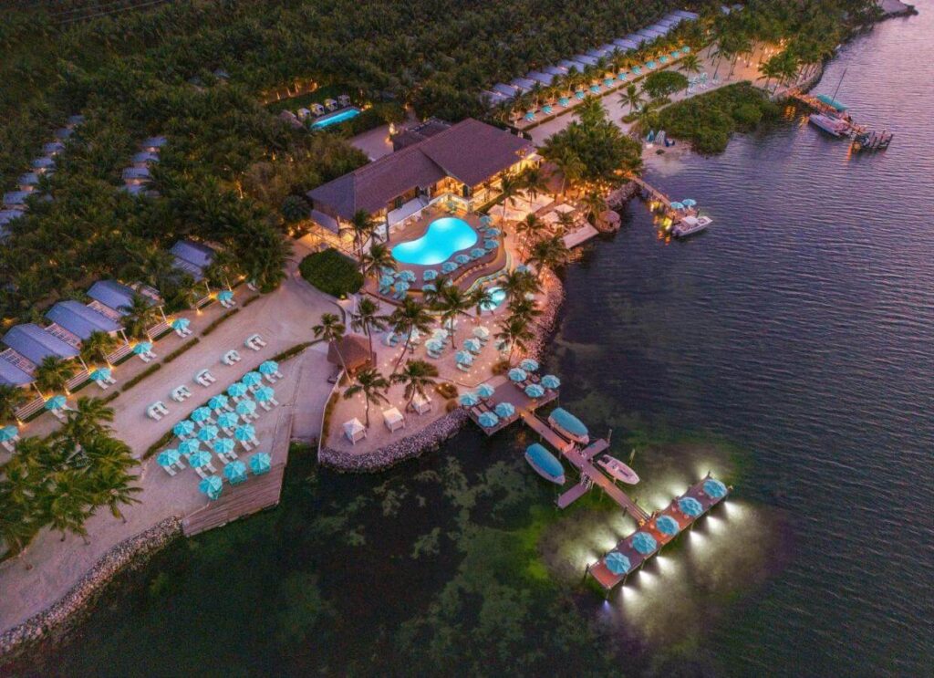 Turquoise cabanas dotting a palm-lined shore at Bungalows Key Largo