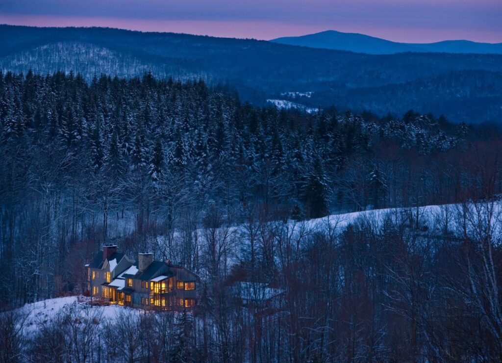 Twin Farms’ warmly lit farmhouse glowing through snow-blanketed Vermont woods