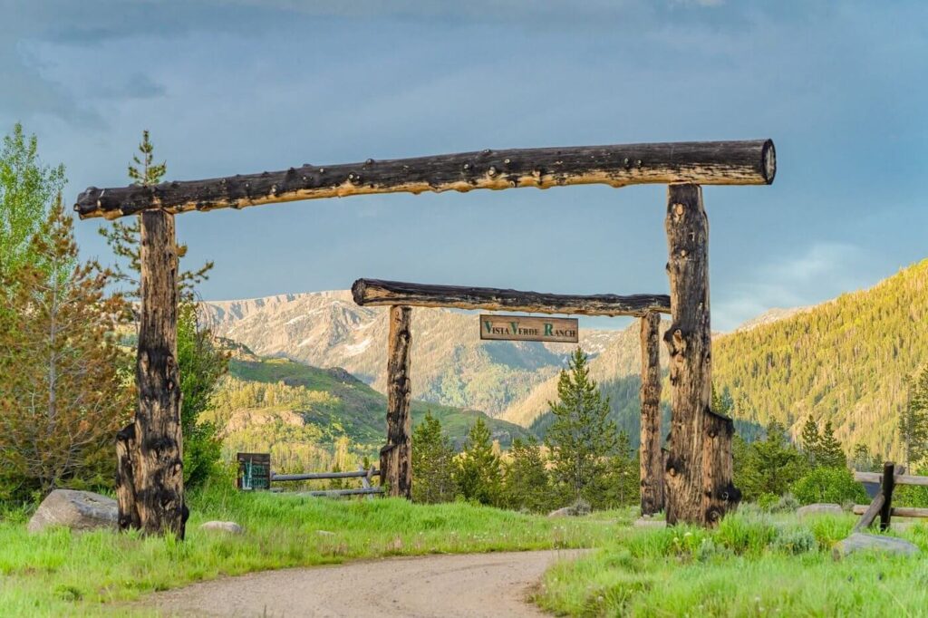 Weathered gate at Vista Verde Ranch frames the soaring Colorado Rockies