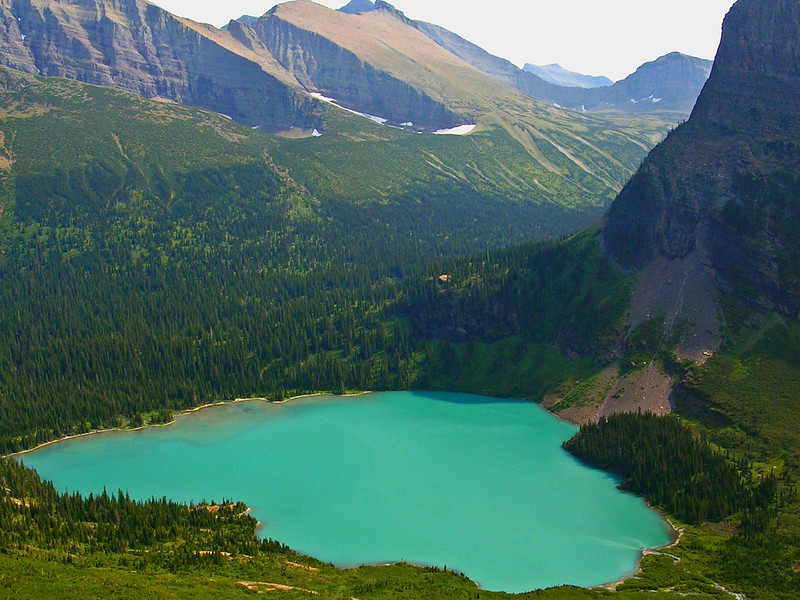A vivid blue basin shimmers beneath towering peaks at Lower Grinnell Lake