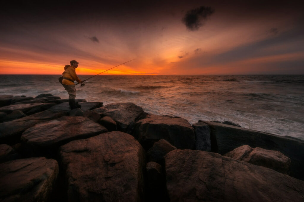 Angler casting at sunset over rugged rocks in Montauk, New York