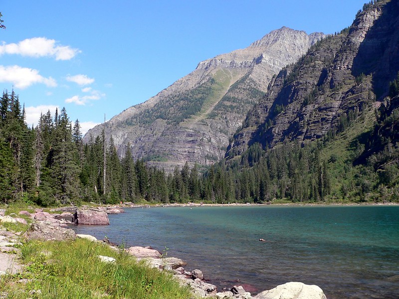 Clear glacial waters lap against rocky shores at Avalanche Lake