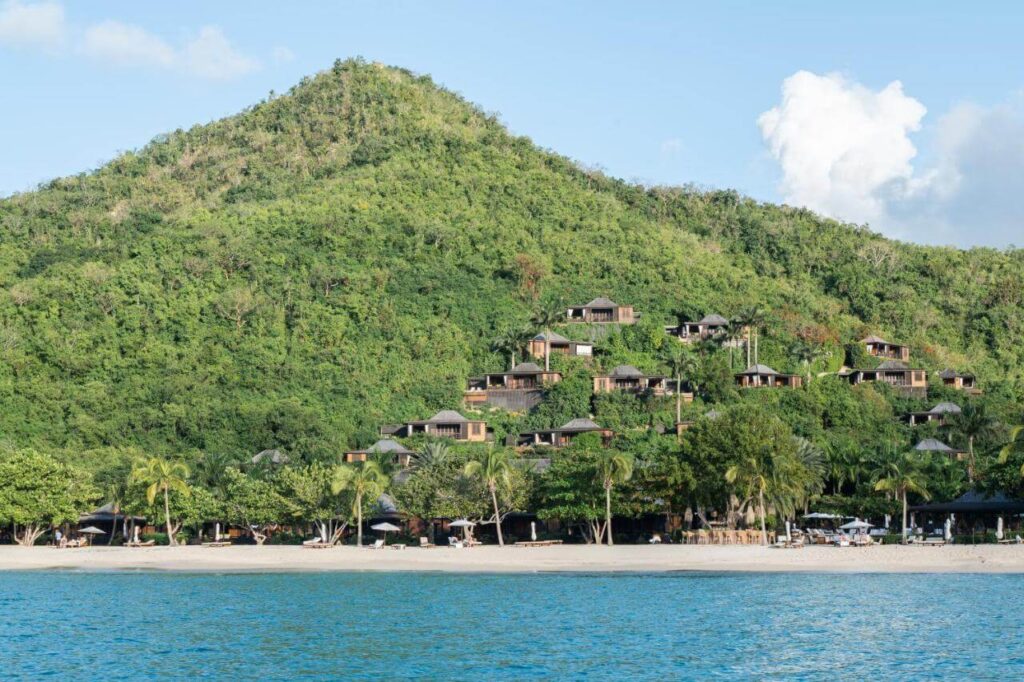 Wooden suites climb the green hillsides above the bay at Hermitage Bay, Antigua