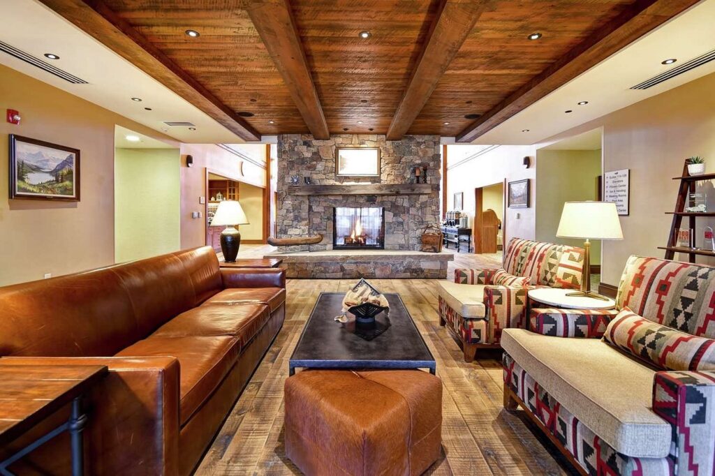 Cozy, wood-beamed lounge area with a stone fireplace at Homewood Suites by Hilton