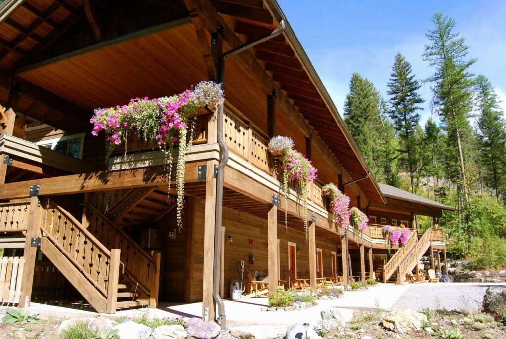 Flower-adorned balconies at Glacier Guides Lodge against a wooded backdrop