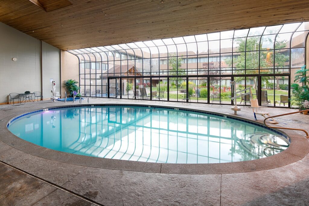Indoor pool framed by glass walls overlooking landscaped gardens at Red Lion Hotel Kalispell