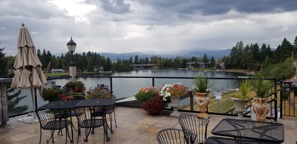 Lakeside terrace with floral urns and mountain views at Swan River Inn